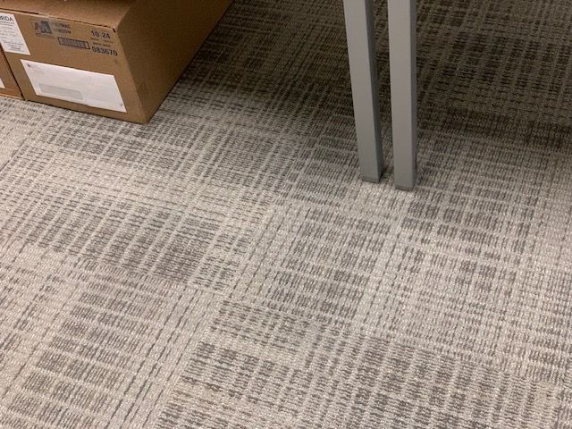 Clean office carpet next to supply boxes following commercial carpet restoration