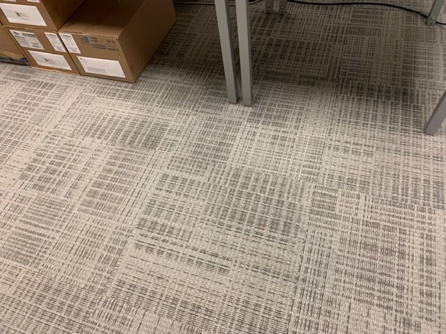 Restored commercial carpet under office table after toner spill cleaning