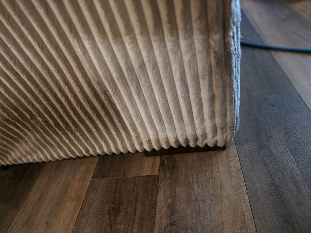 Dark dirt line packed along the base trim of a white sofa before upholstery cleaning