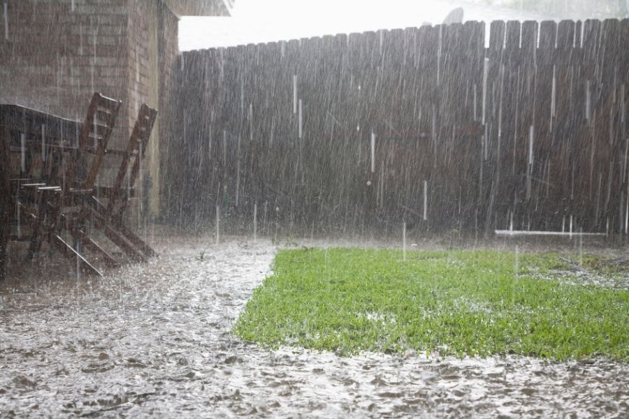 Heavy rain flooding a fenced backyard with standing water rising around patio chairs in Largo FL