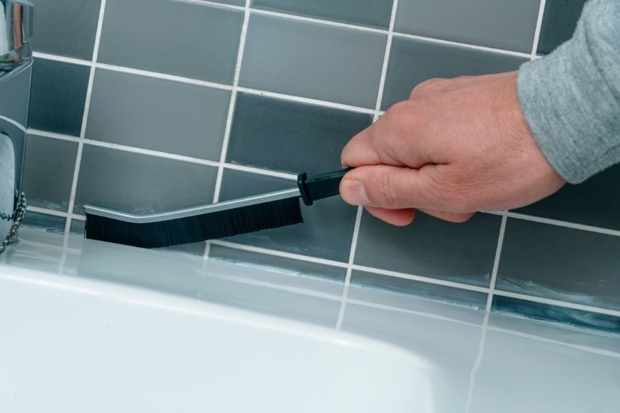 Close-up of steam cleaning equipment lifting dirt from tile and grout in a residential bathroom