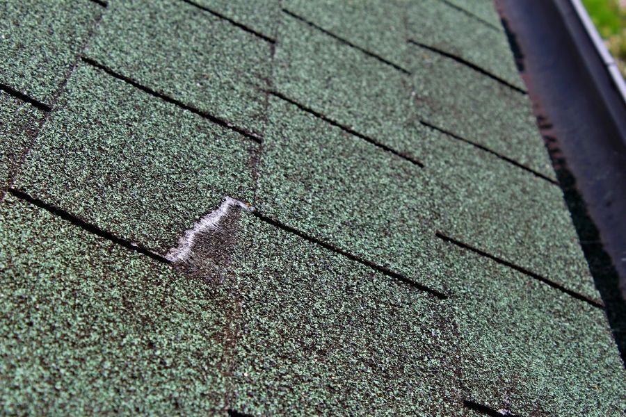 Storm-damaged roof showing lifted shingles and exposed underlayment after a Florida hurricane