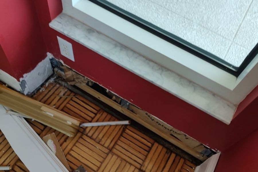 Professional baseboard removal during water damage restoration in a residential living room