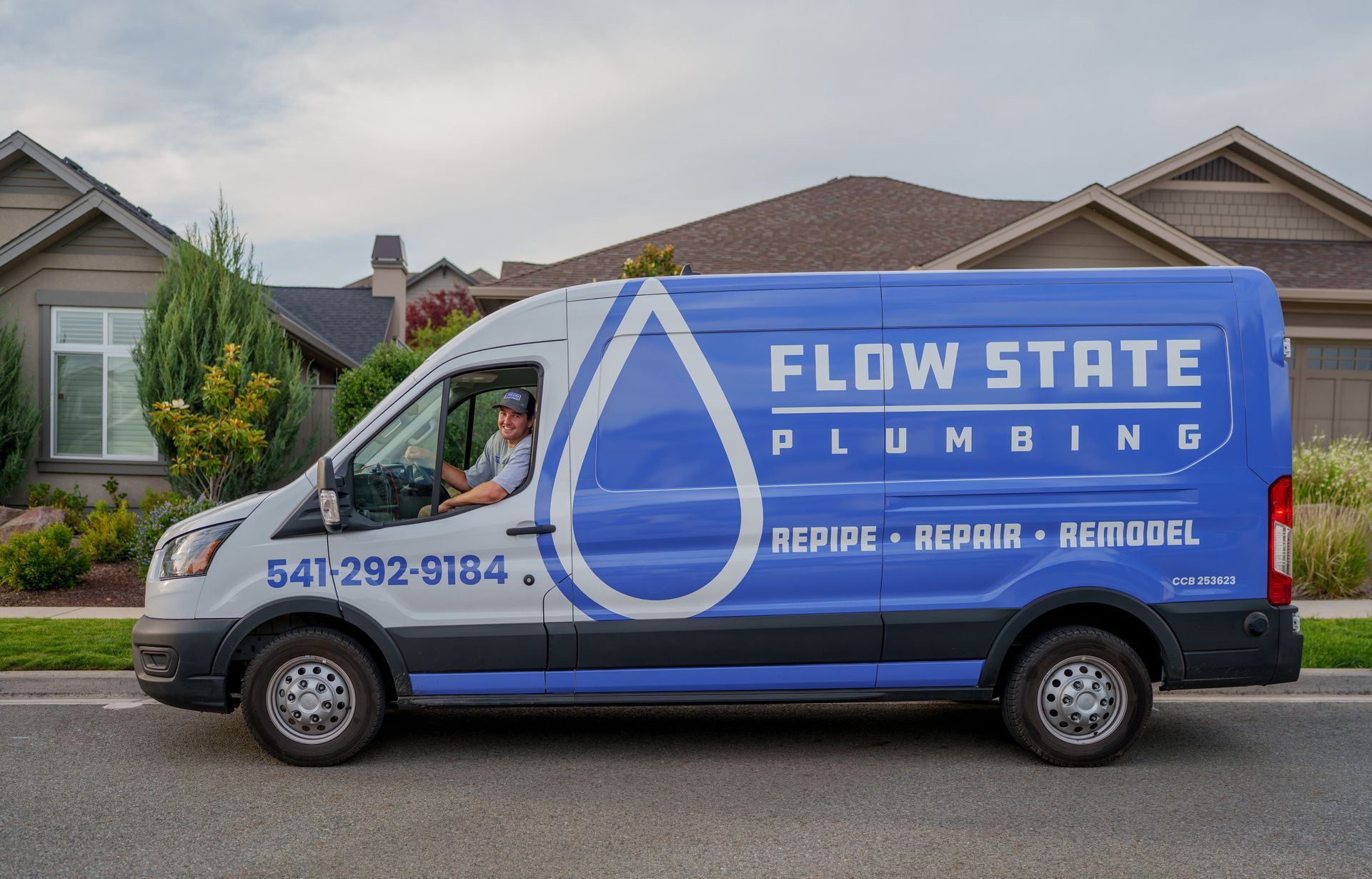Owner of Flow State Plumbing in his branded work van outside of a home in Southern Oregon.