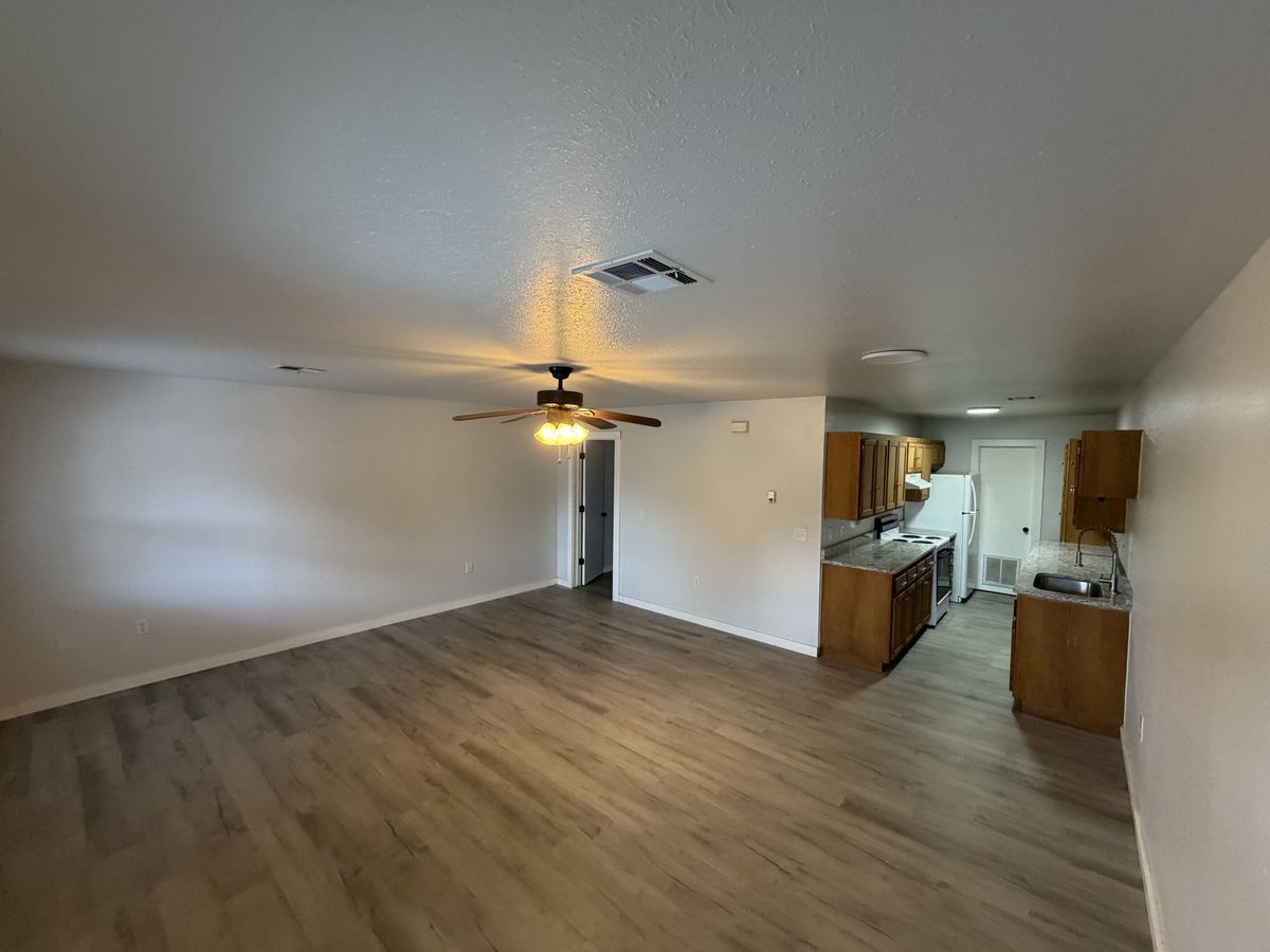 Northbrook Apartments living room with new vinyl plank floors and a ceiling fan, open to a kitchen with granite counters