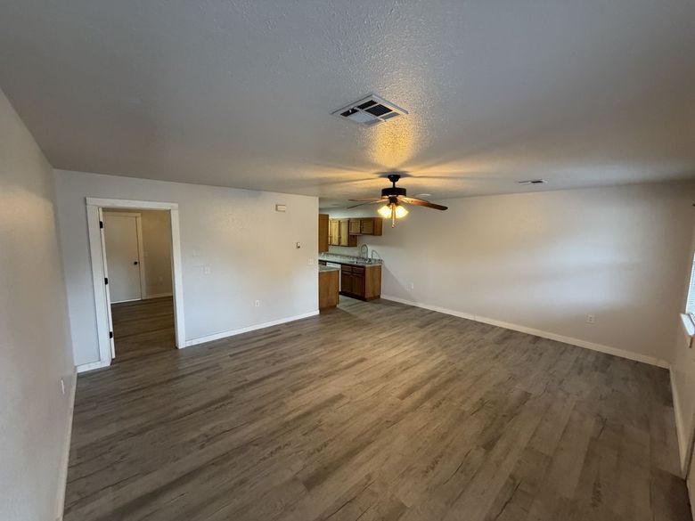 Spacious Northbrook Apartments living room with vinyl plank floors and a ceiling fan, kitchen in the back corner