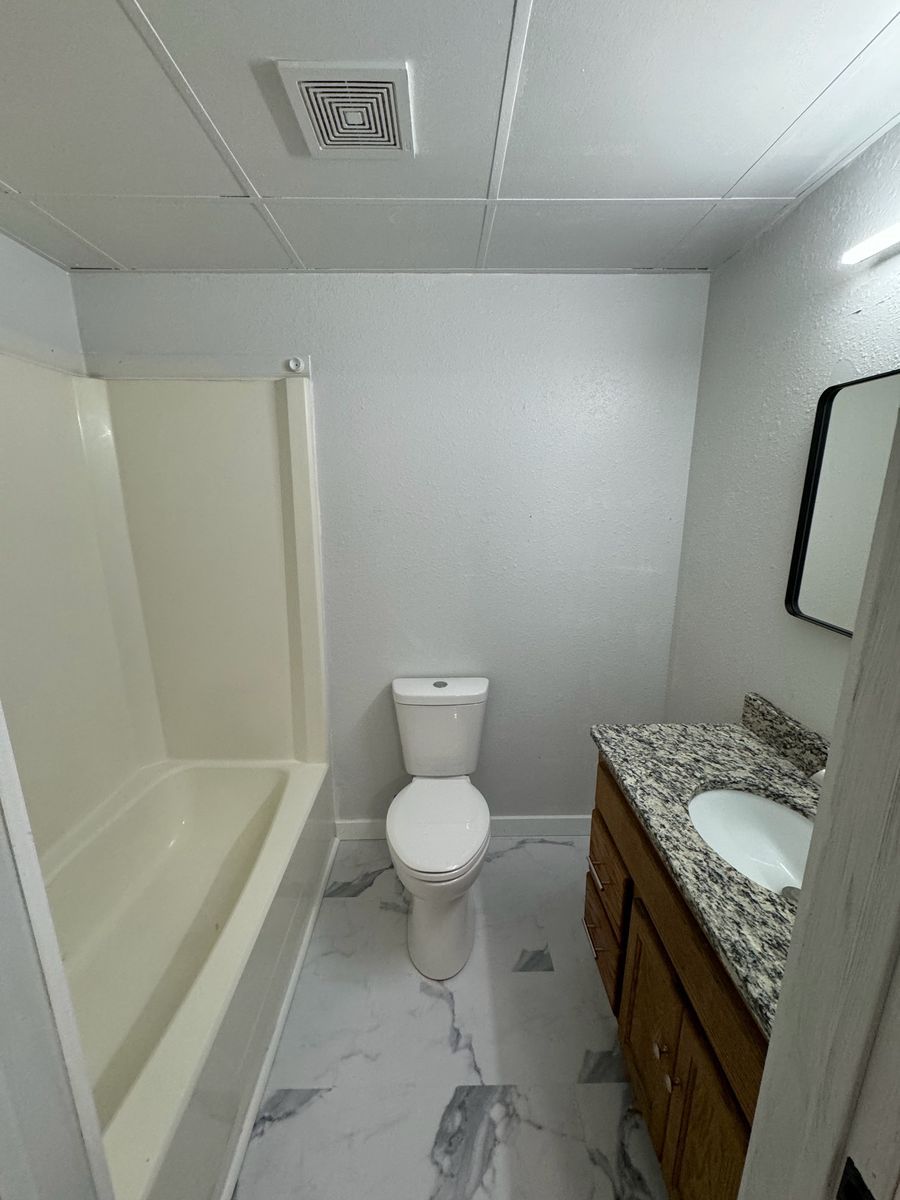 Renovated Northbrook Apartments bathroom with tile floor, tub and shower, and wood vanity