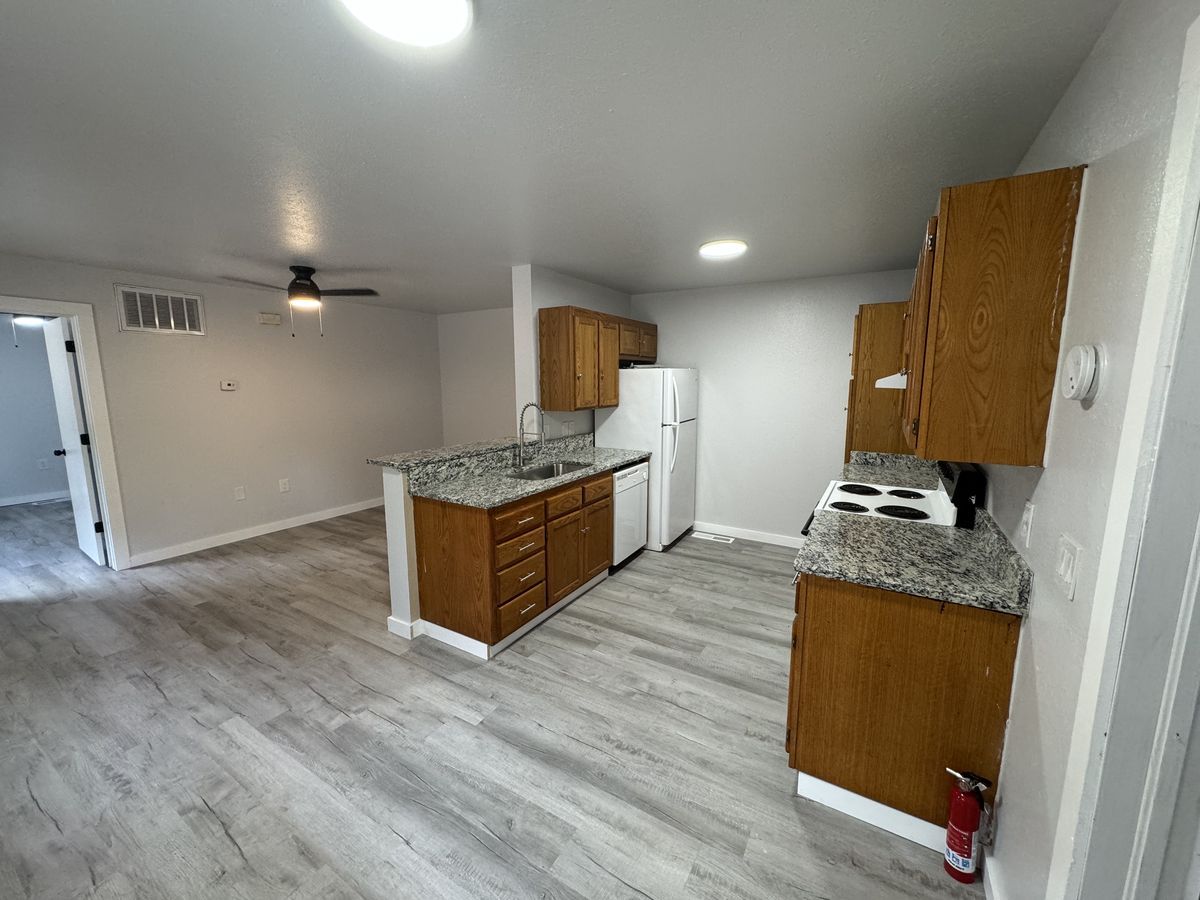 Renovated Northbrook Apartments kitchen with wood cabinets, granite-look counters, breakfast bar, and plank floors