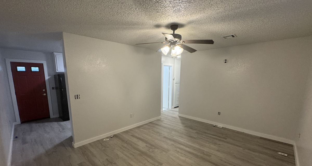 Empty living room with wood-look flooring and a ceiling fan