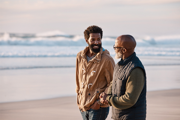 two men are walking on the beach and shaking hands .