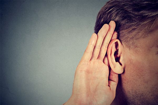 a man is listening to something with his hand on his ear .