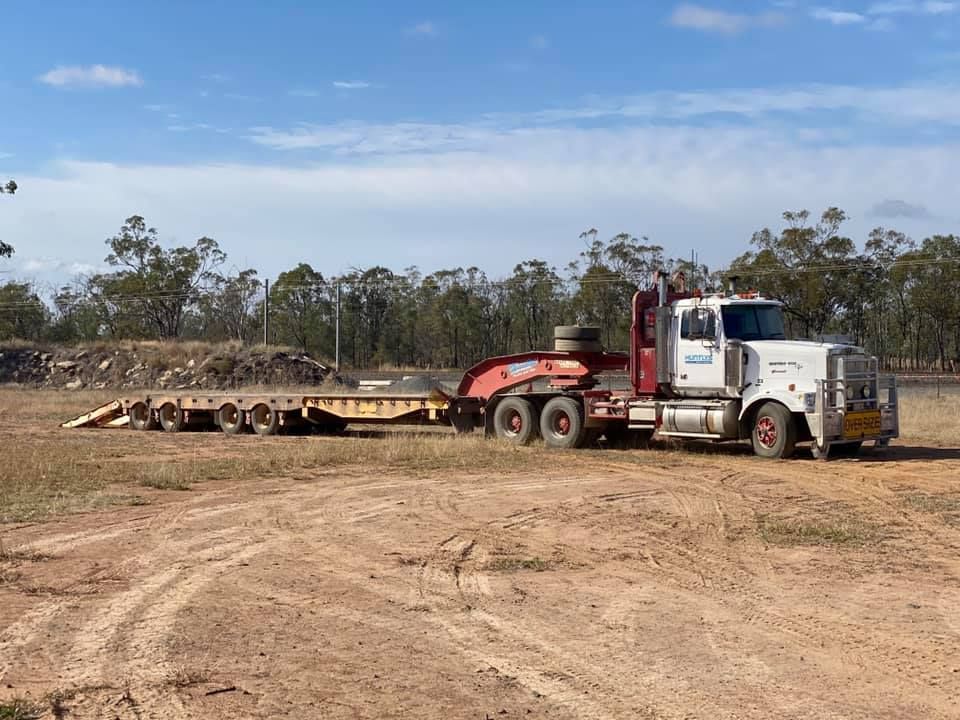 Truck With a Long Trailer Parked on a Dirt Lot — Huntlys Heavy Equipment In Gracemere, QLD