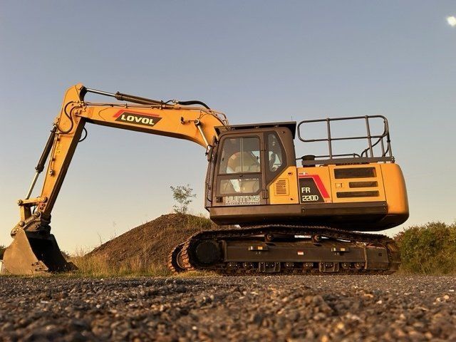 Yellow Excavator on a Gravel Surface Next to a Dirt Pile Under a Blue Sky — Huntlys Heavy Equipment in Gracemere, QLD