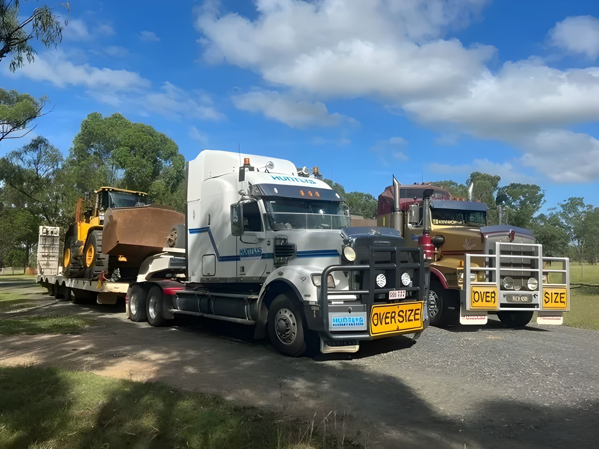 Two Semi-trucks, One Hauling Yellow Construction Equipment — Huntlys Heavy Equipment in Gracemere, QLD