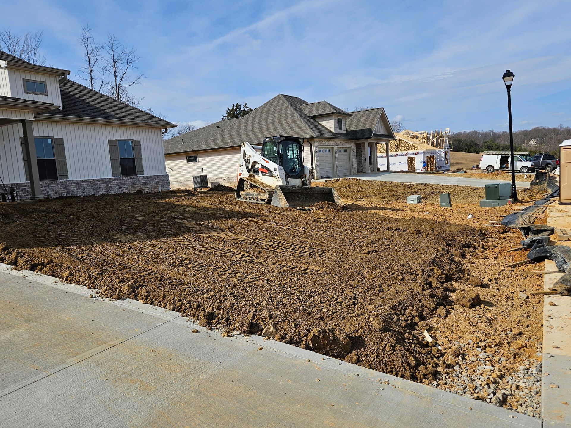 Suburban construction site with a skid steer leveling dirt in front of new houses