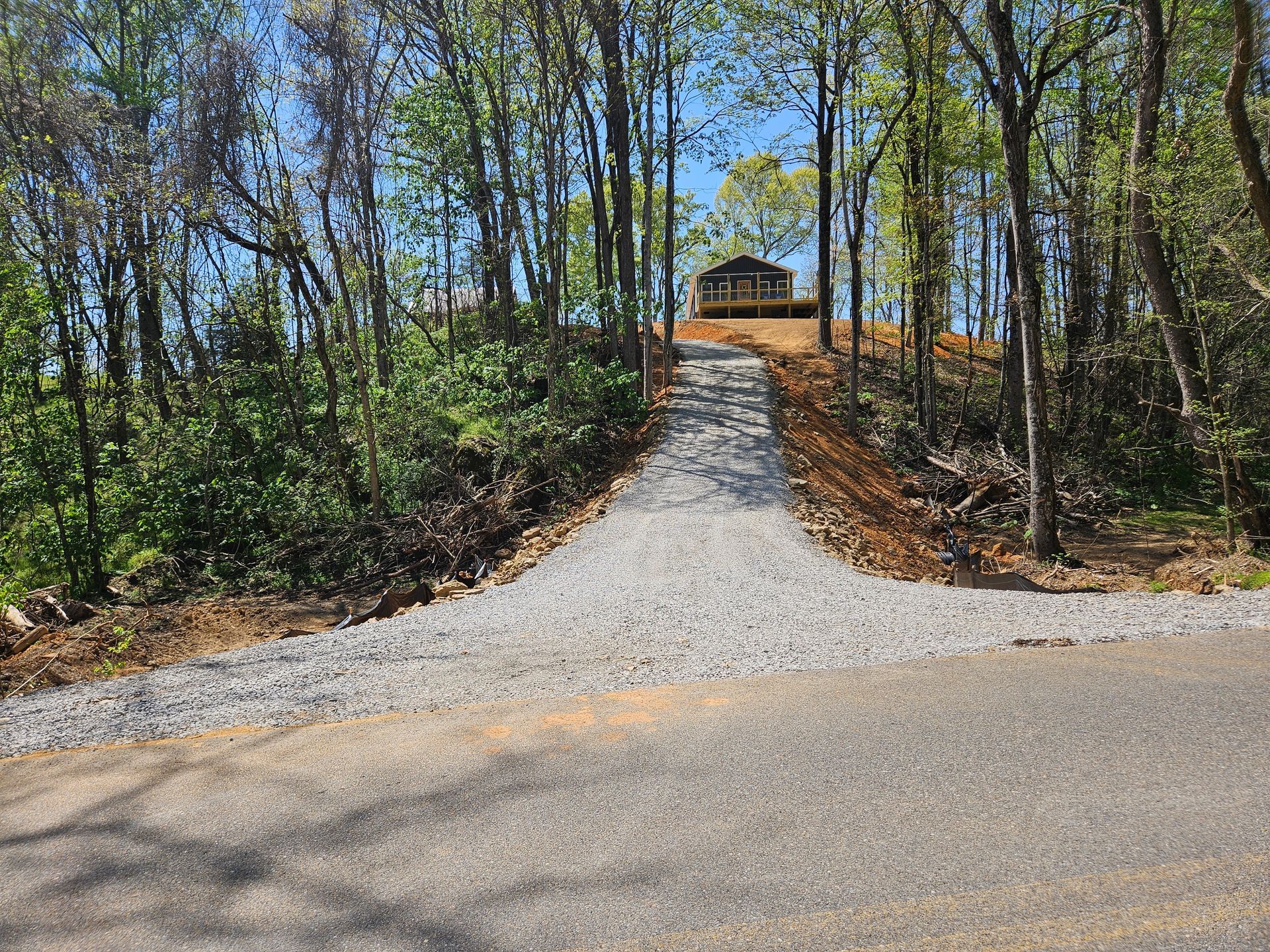 Gravel path leading uphill through a wooded area to a small pavilion at the top