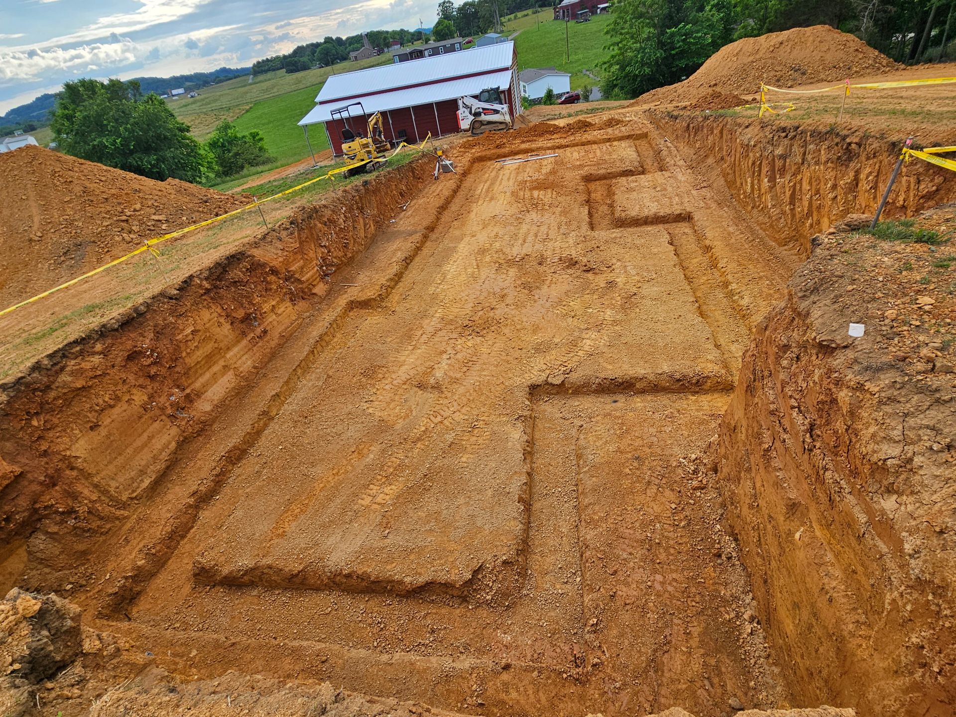 Excavated dirt path with stepped trench work at a construction site under cloudy skies