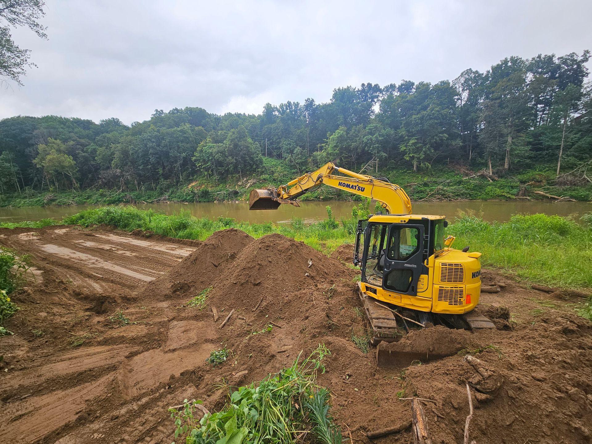 Yellow excavator digging soil at a construction site with trees in the background