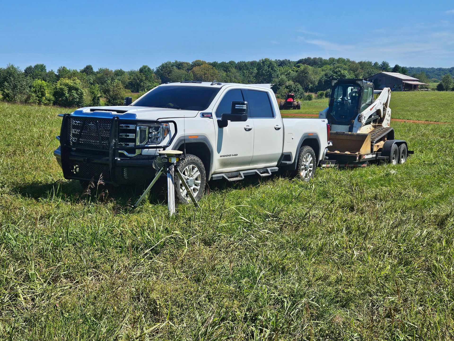 White pickup truck with front loader in a green field on a sunny day