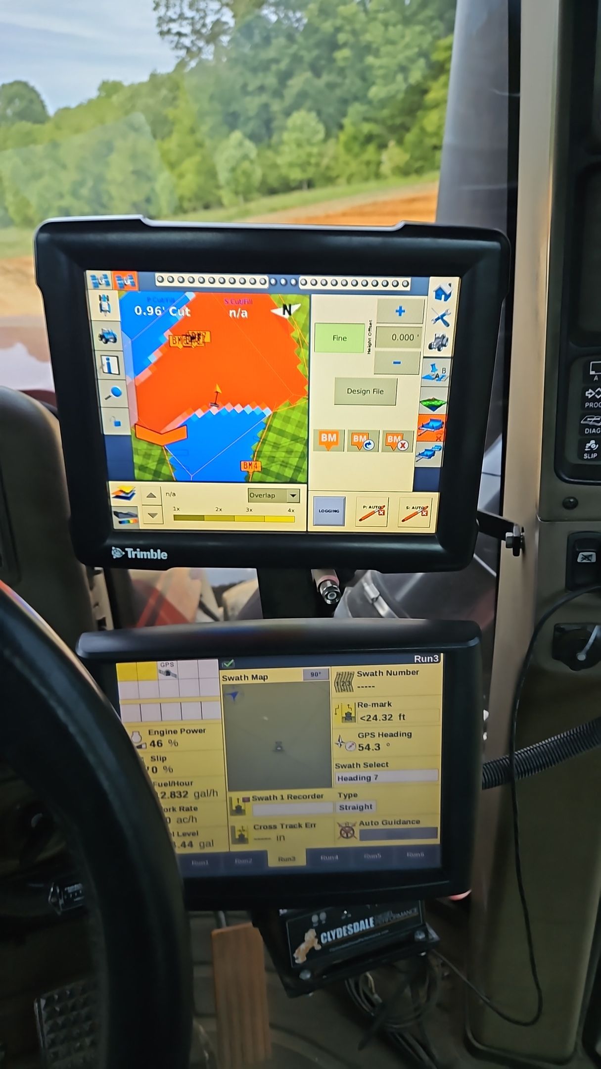 Two in-cab GPS screens showing colorful field maps and tractor controls inside a vehicle cab