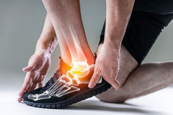 Man holding painful ankle, highlighted bones show injury.
