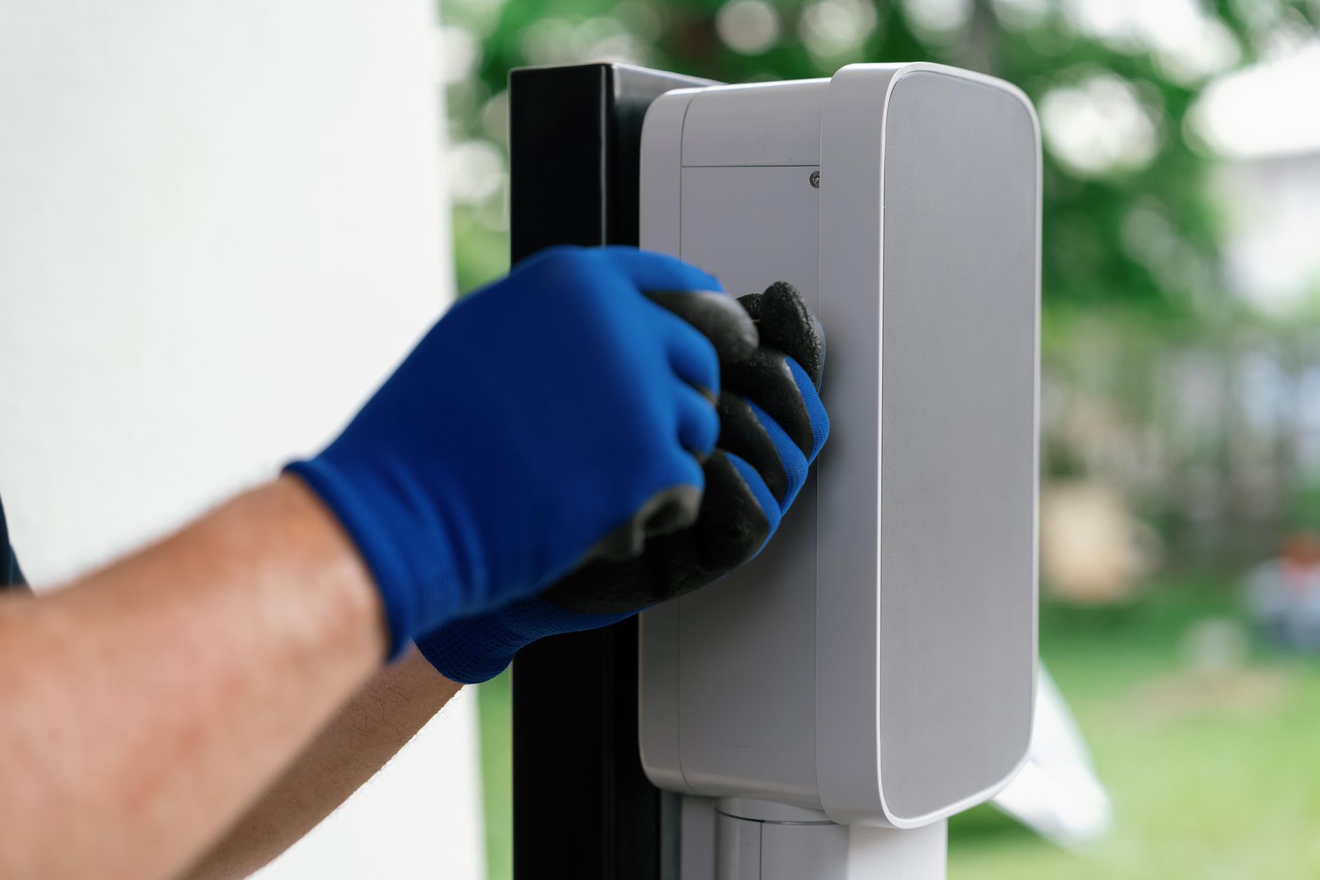 Main gantée nettoyant un appareil extérieur gris fixé sur un poteau