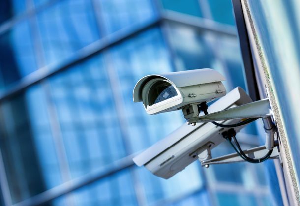 Telecamere di sicurezza installate su un edificio, che inquadrano la facciata in vetro di un ufficio.