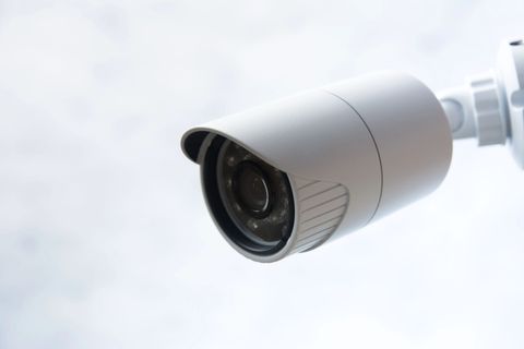 Telecamera di sicurezza bianca montata all'esterno, angolata a sinistra su uno sfondo chiaro.