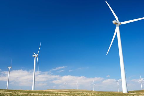 Turbine eoliche su una pianura erbosa sotto un cielo azzurro brillante