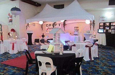 A banquet room set up for an event, featuring round tables with white and black tablecloths under a decorative white tent.