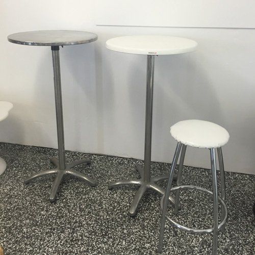 Two tall, round cocktail tables and a matching stool with white seats and chrome legs standing on a speckled floor.