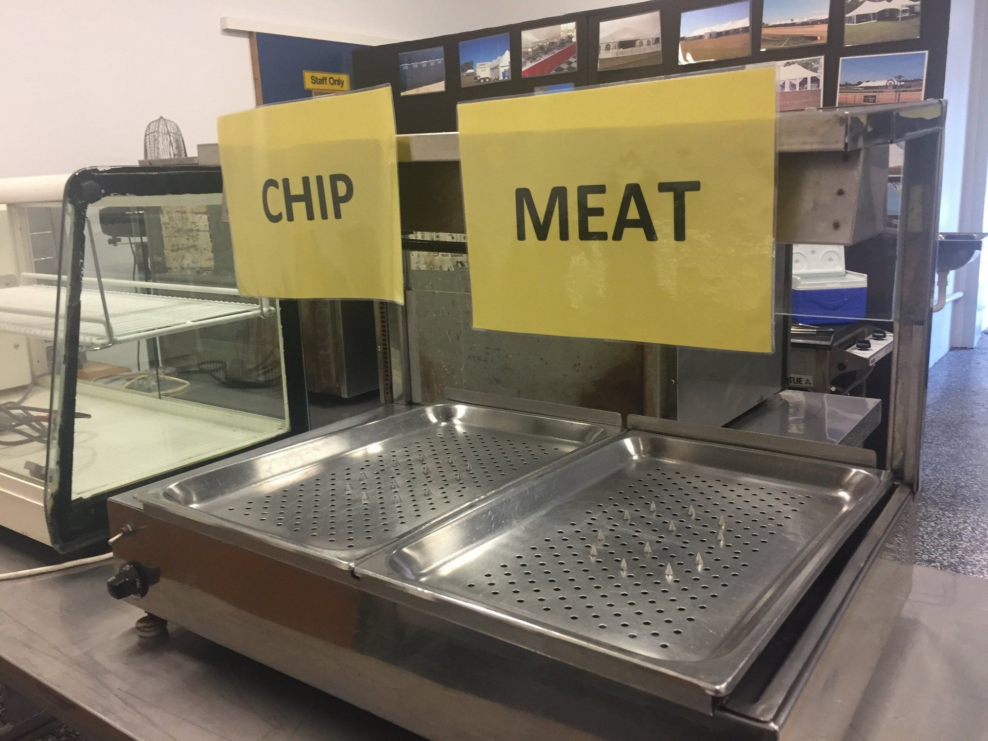A stainless steel countertop food warmer with two trays and yellow signs labeled 