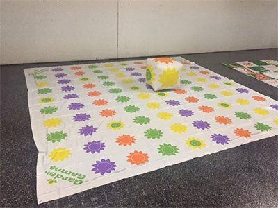 A large, colorful Garden Games mat featuring rows of sun symbols in yellow, green, orange, and purple, with a soft die.