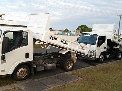 Two white dump trucks with