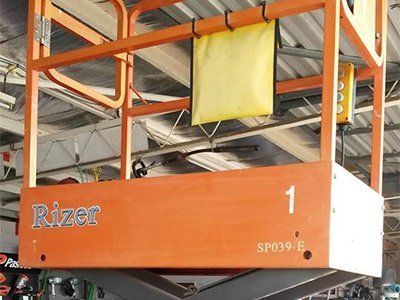 An orange scissor lift platform labeled