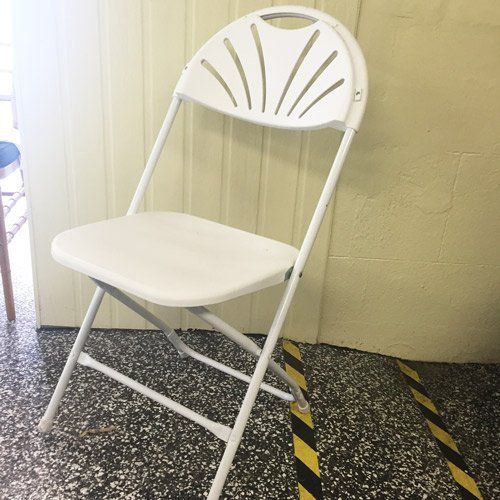 A white folding chair with a decorative, fan-shaped backrest standing on a speckled floor near a light-colored wall.
