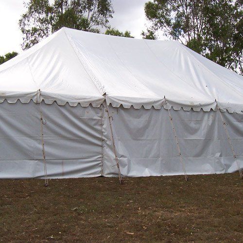 A large white event tent with a scalloped edge stands on a grassy field under a cloudy sky.