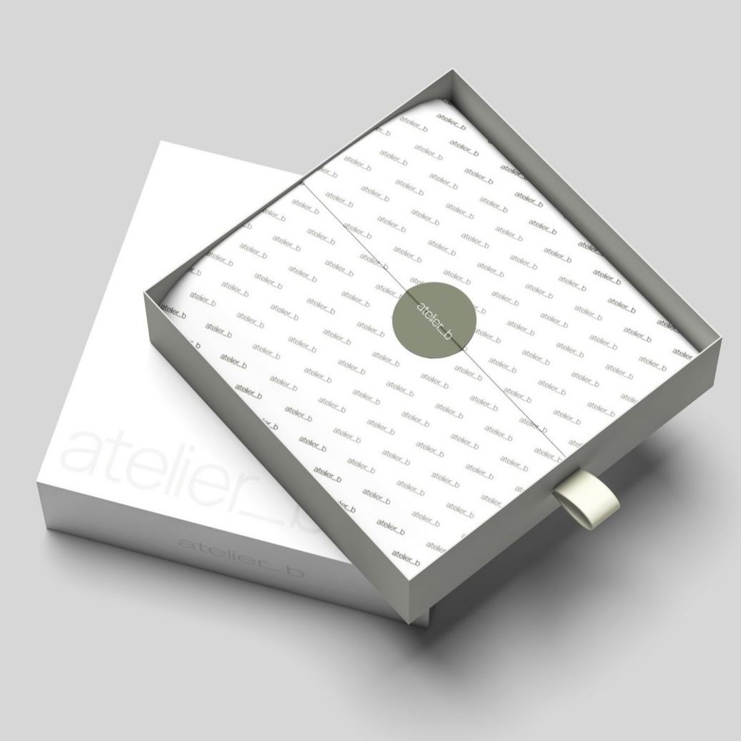 Open white box with gray lid, tissue paper, and green sticker. The lid has a pull tab and rests beside the base.