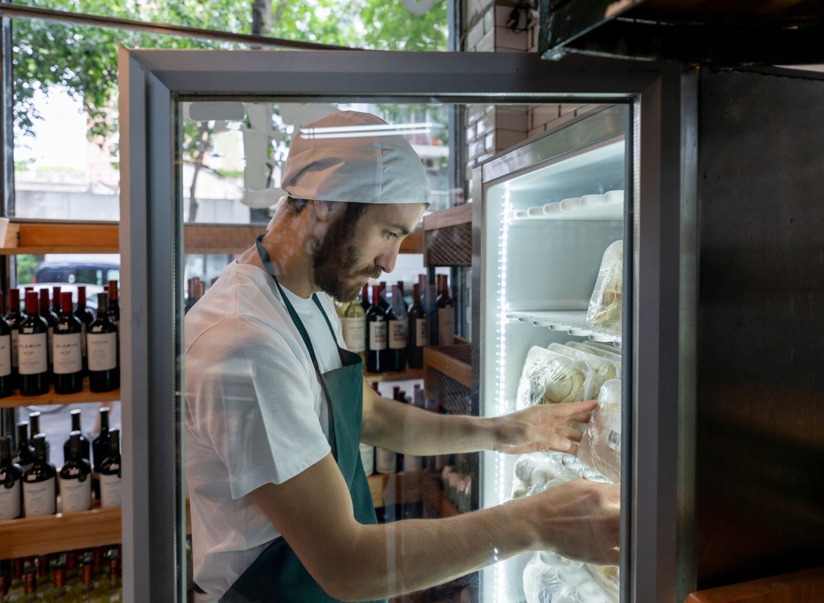 Person stocking items in a refrigerated display case in a store