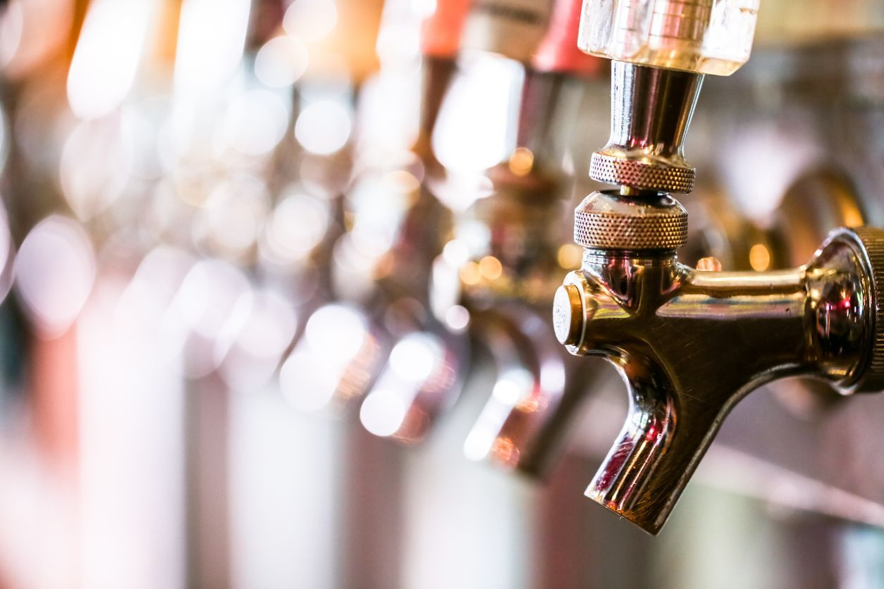 Close-up of beer taps in a bar, with a brass tap in focus and others blurred behind it