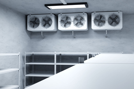 Empty white industrial room with wall-mounted fans, shelving, and a large white table