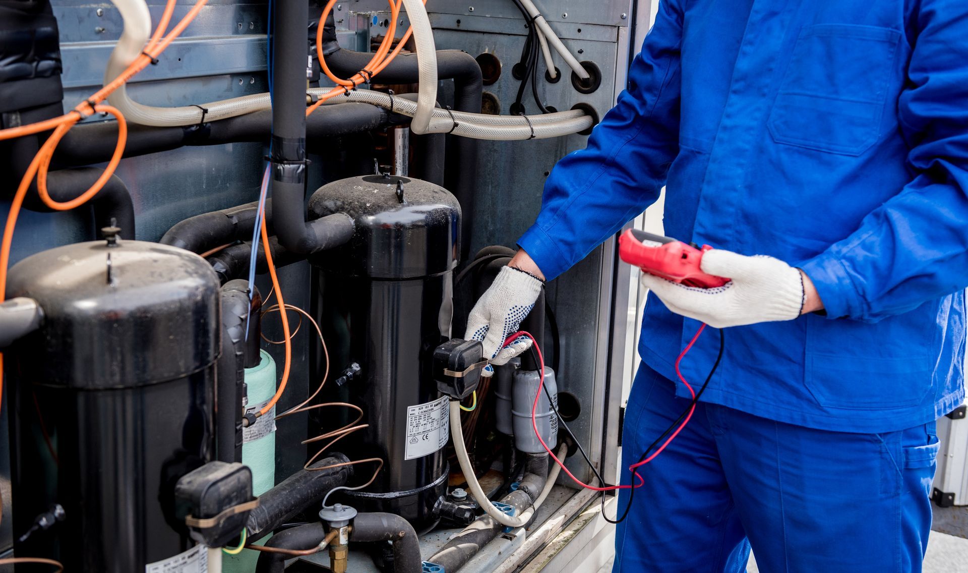 Commercial refrigeration technician inspecting a walk-in cooler condenser unit during summer.