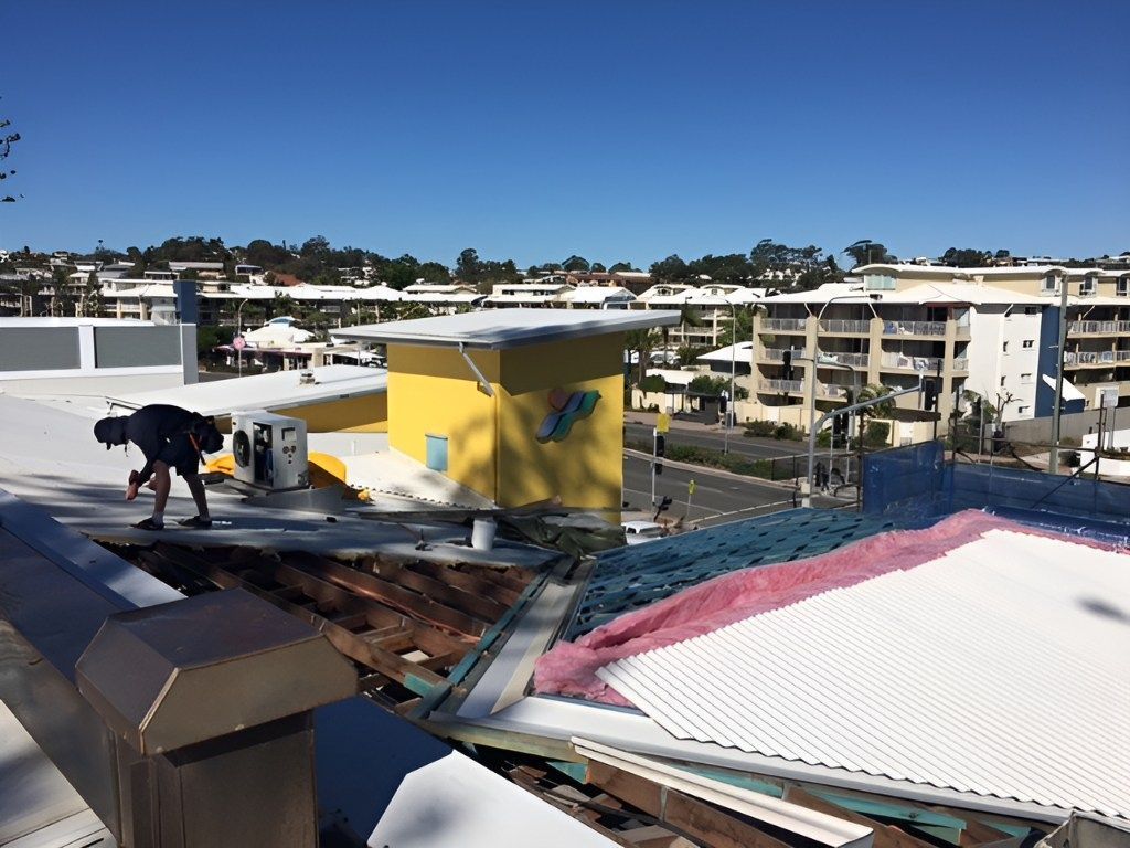 A Man is Working on the Roof of a Building — Roofing Revamped in Warana, QLD