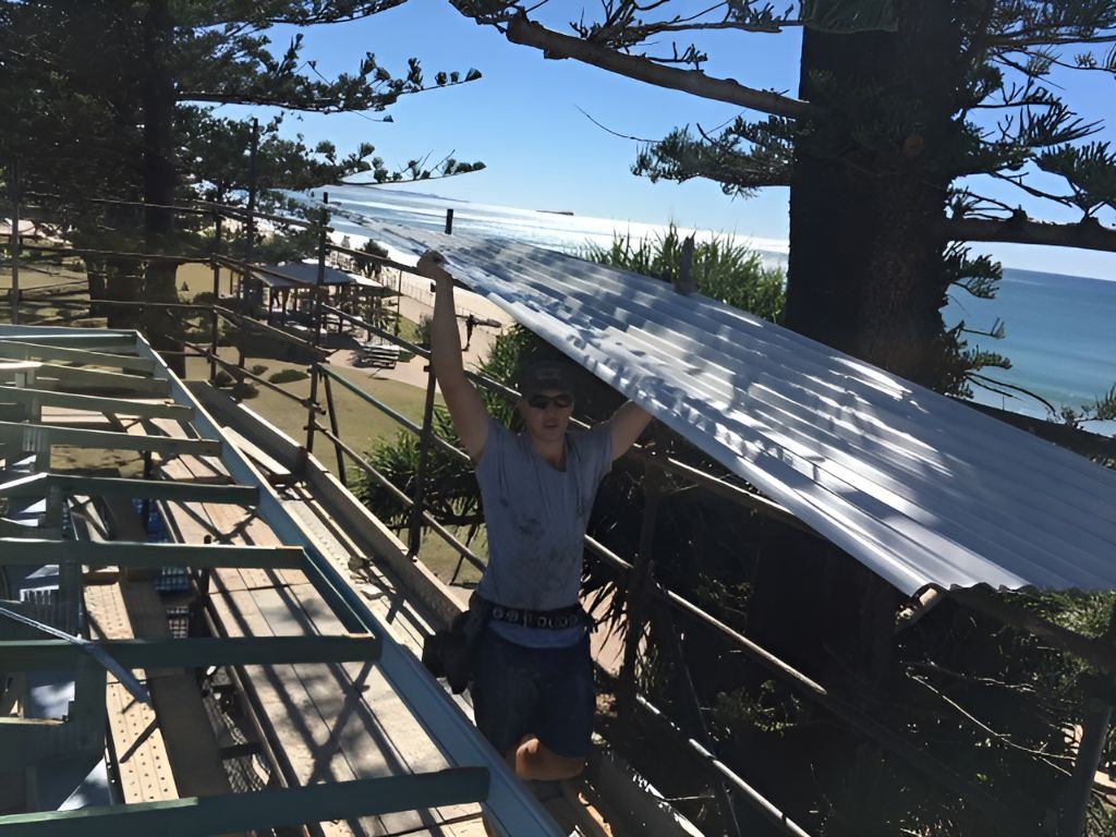 A Man is Holding a Large Piece of Metal Over His Head — Roofing Revamped in Caloundra, QLD