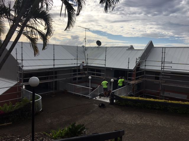 A Group of People Are Working on the Roof of a Building — Roofing Revamped In Maroochydore, QLD
