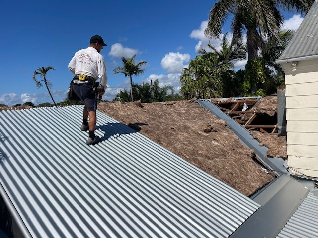 A Man is Working on the Roof of a Building — Roofing Revamped In Gympie, QLD