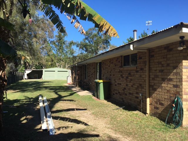 A Brick House With a Green Trash Can in Front of It — Roofing Revamped in Maroochydore, QLD