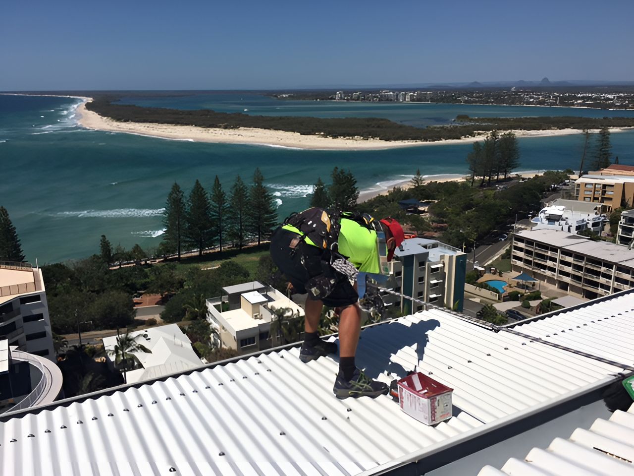 A Man is Fixing the Roof of a Building Overlooking the Ocean — Roofing Revamped in Nambour, QLD