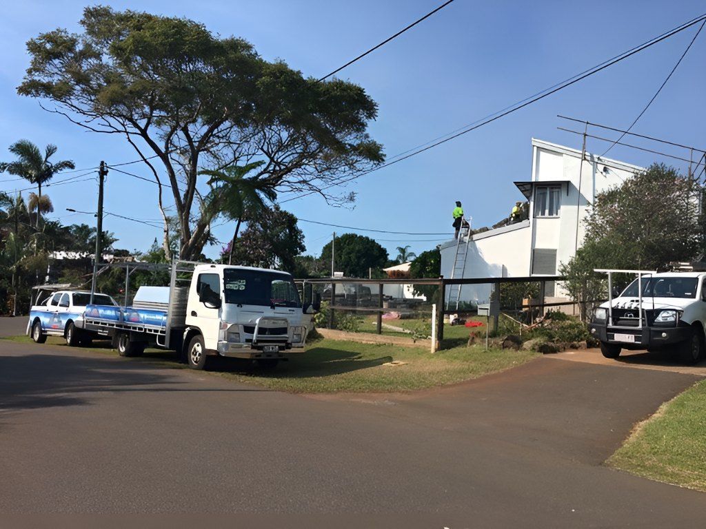 A Row of White Trucks Are Parked on the Side of the Road — Roofing Revamped In Coolum Beach, QLD
