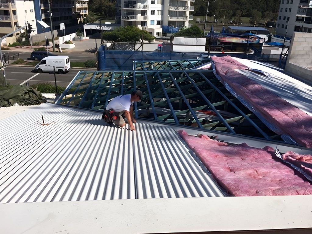 A Man is Working on the Roof of a Building — Roofing Revamped in Maroochydore, QLD